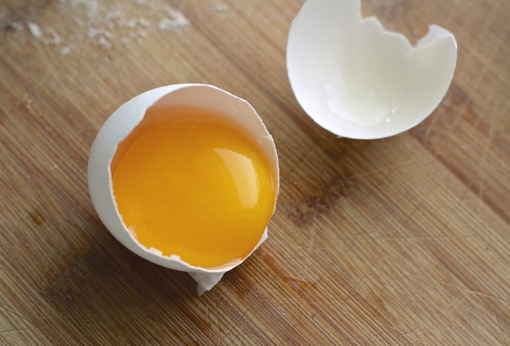 Egg cracked open showing raw yolk inside.
