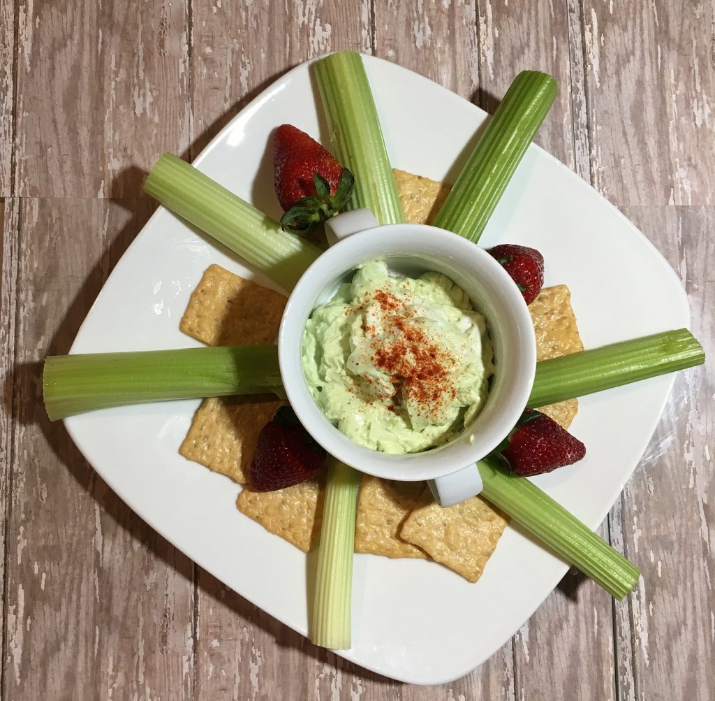 Plate of dip with crackers, strawberries and celery.