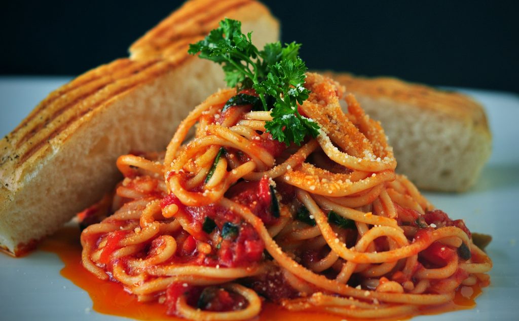 Spaghetti on plate garnished with parsley and cut bread.