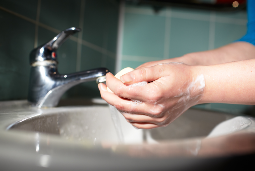 Woman washing hands in sink with bar of soap.