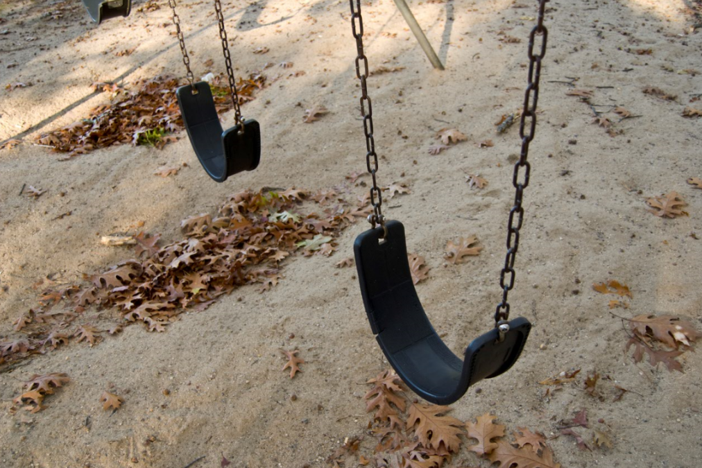 Two empty swings on playground during fall.
