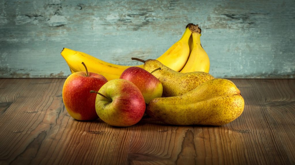Bananas, apples and pears on a wood table.