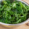 Chopped kale in bowl with dressing and seasonings.