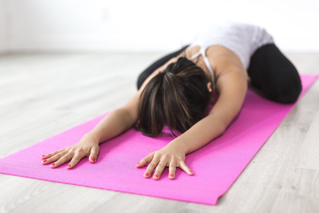 Woman stretching out on a pink yoga mat.