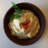 hummus in a bowl, garnished with parsley and paprika.