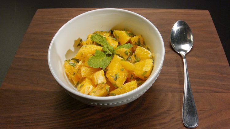 Bowl of cinnamon oranges, topped with mint.
