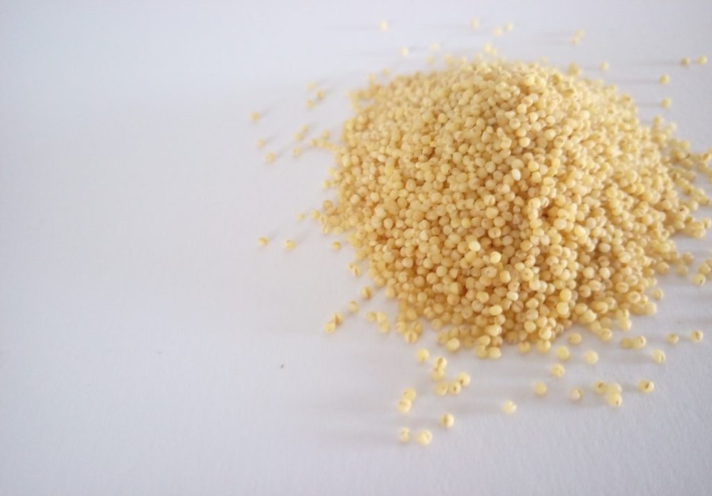 Cooked millet on a pile on a white table.