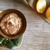 lemony white bean dip, on a plate with cut vegetables, including broccoli, red bell pepper and cucumber.