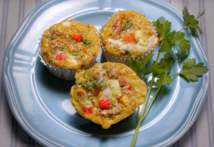 Individual egg frittatas on a plate, garnished with fresh parsley.