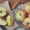 Bowl of whole apples beside small cutting board with cut apples.