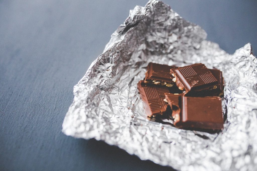 Small squares of chocolate on top of aluminum foil wrapper.