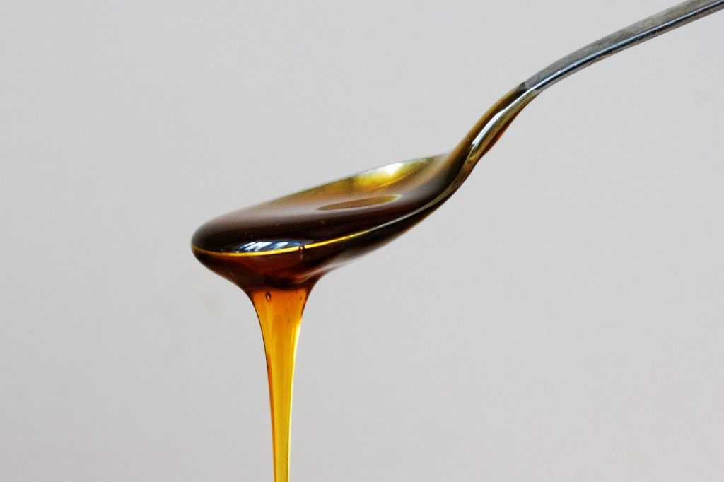 Honey slowly dripping off of a spoon.