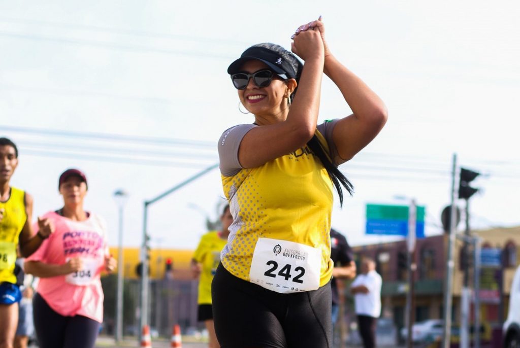 Woman holding hands up in the air in celebration after running race.