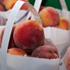 Fresh peaches in paper bags outside.