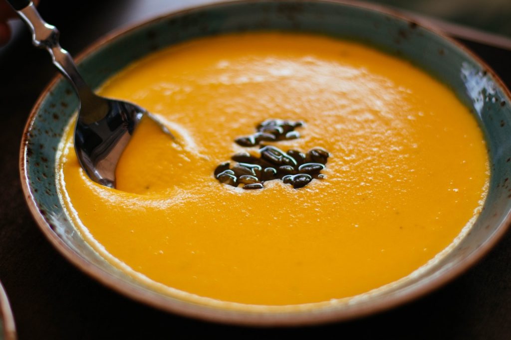 Bowl of orange soup topped with black beans.
