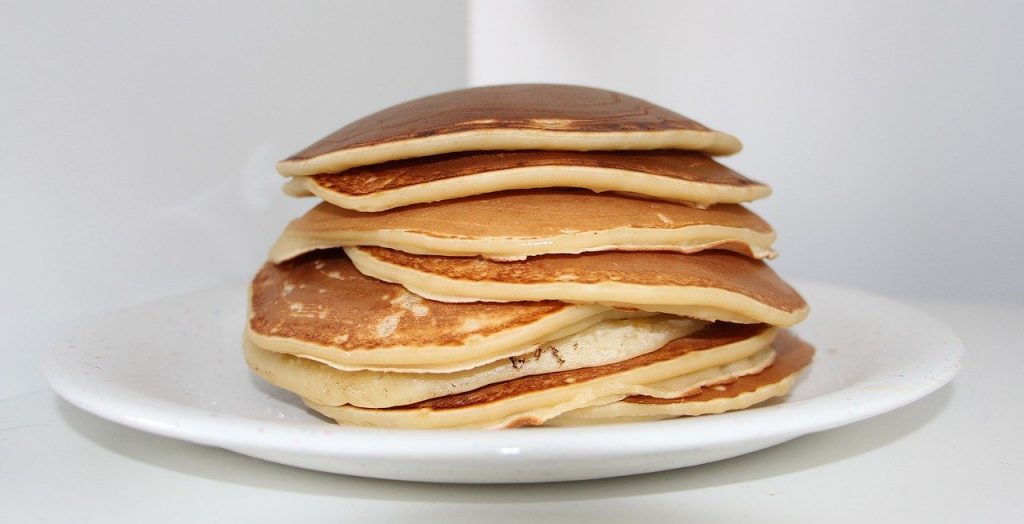 Pancakes on white plate stacked 8 pancakes high.