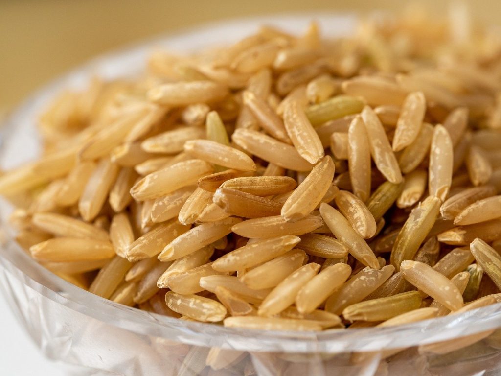 Uncooked brown rice in glass dish.