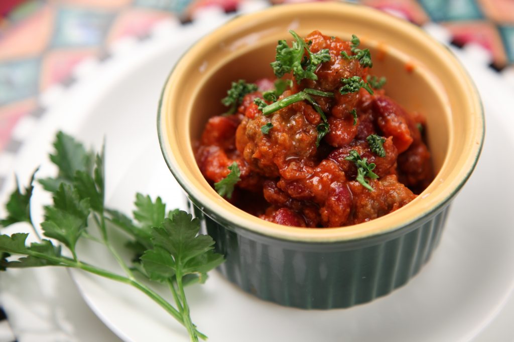 Small bowl of chili topped with parsley.