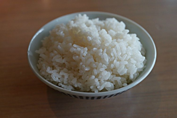 Cooked white rice in small bowl on table.